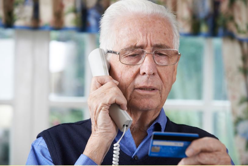 Senior holding credit card on phone