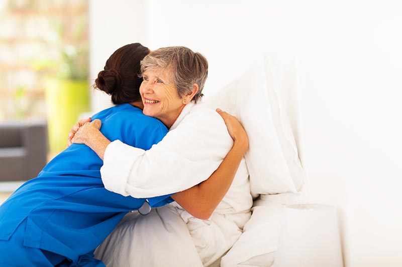 Caregiver and Senior Hugging