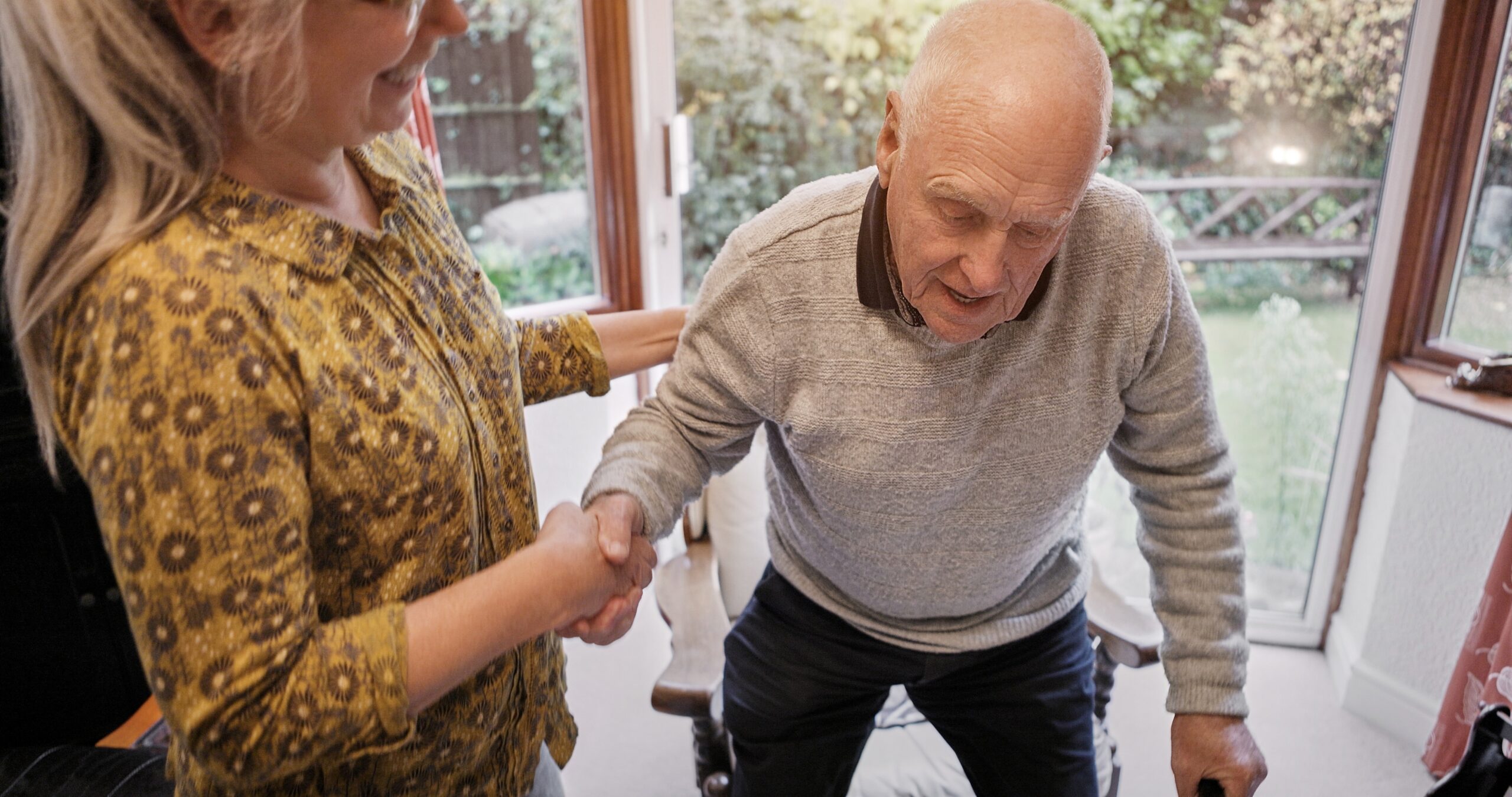 Caregiver helping elderly family member get up from chair