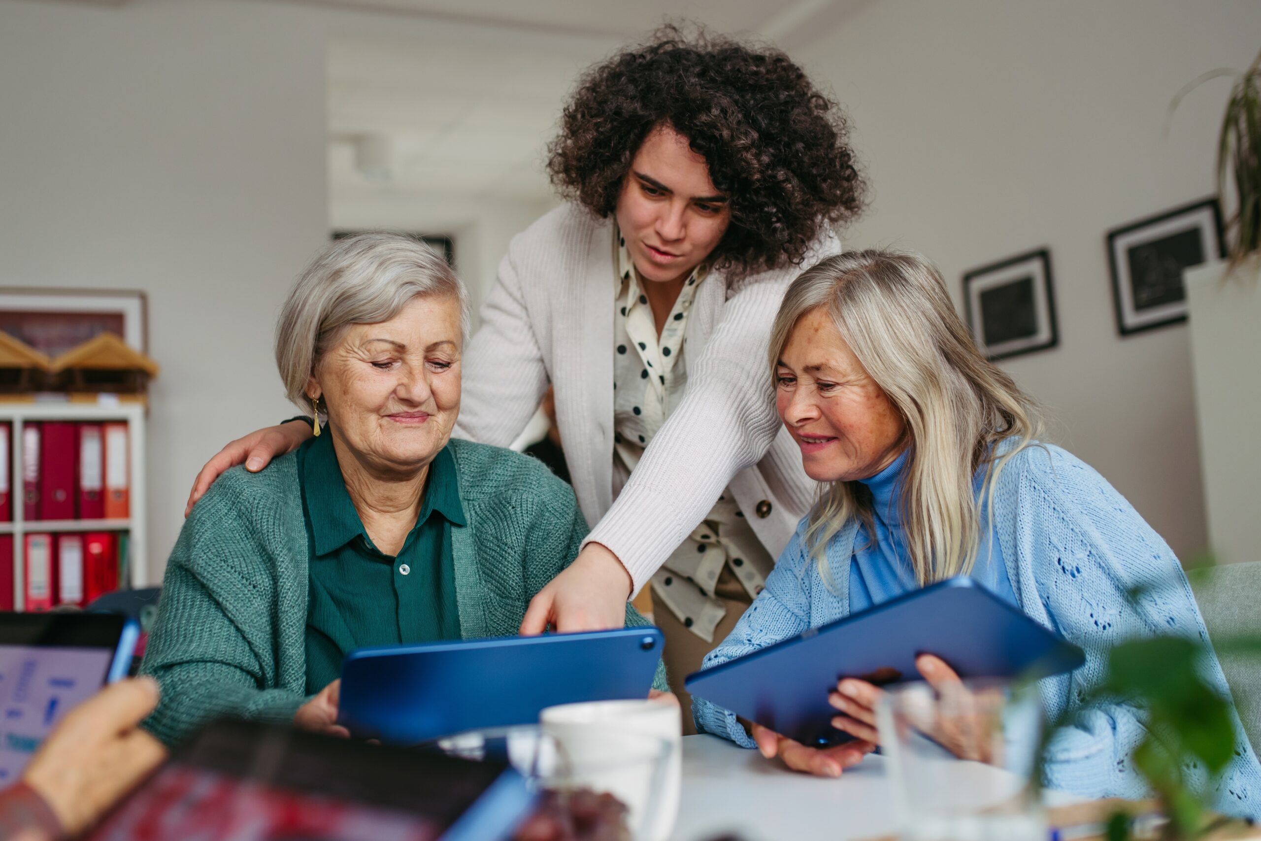 A nurse leans over a woman's shoulder while she shows her and her friend some tips for online safety.