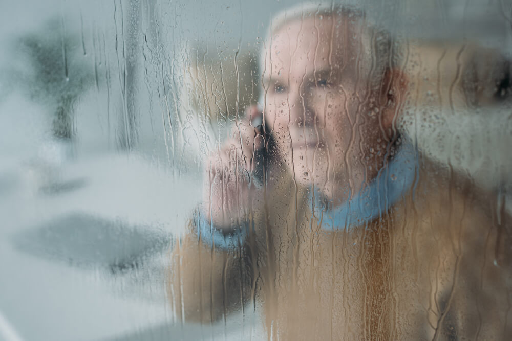 senior on the phone through rainy window
