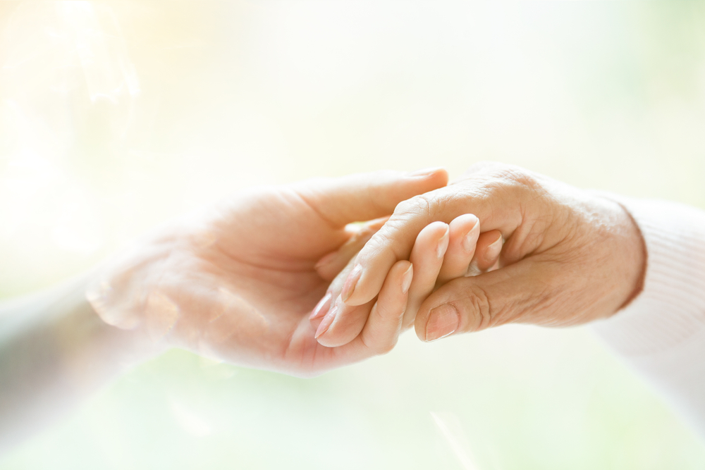 Caregiver holding senior's hand