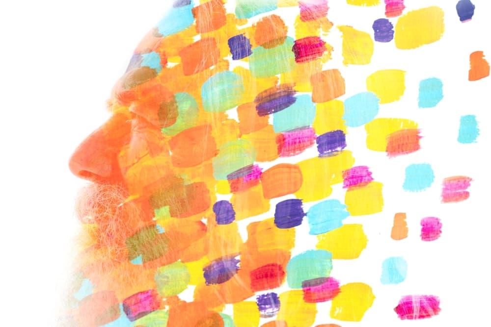 The face of a senor man that breaks into patches of multi-colored paint to represent the positive effect of chromotherapy on seniors.