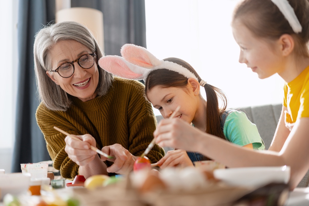 Senior teaching grandchildren how to paint eggs for Easter.
