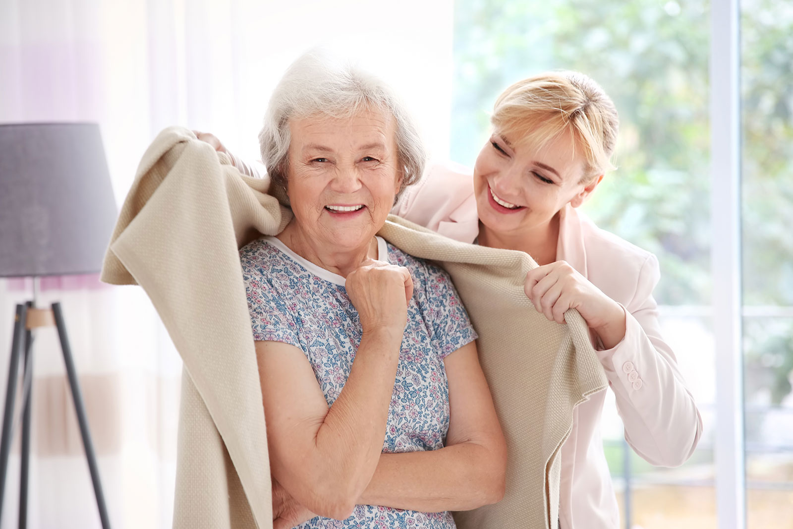 caregiver wrapping senior in a warm blanket