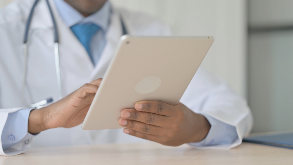 Doctor scrolling on tablet to monitor patient health and brain vitals