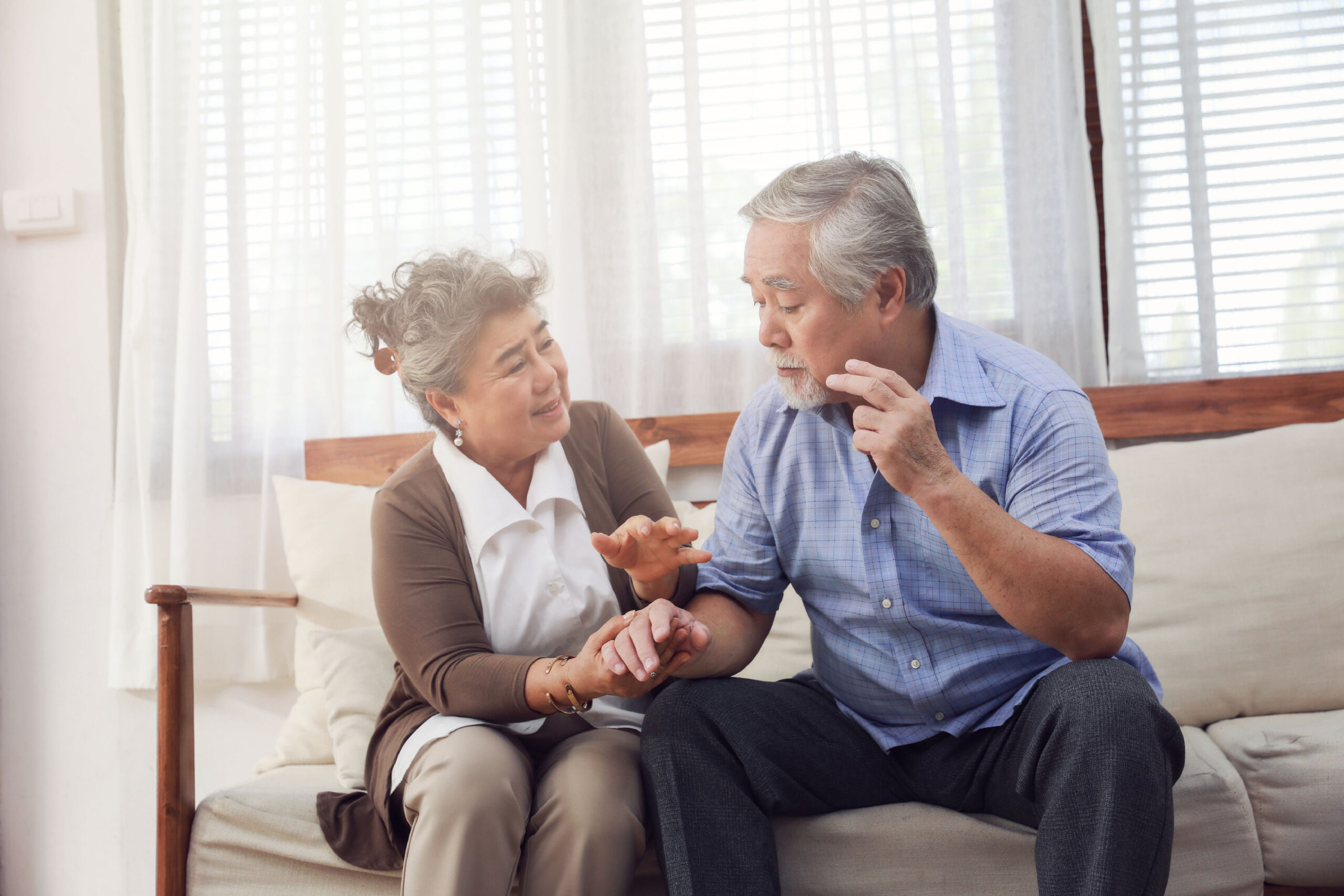 senior woman and man sit out couch talking about memory care