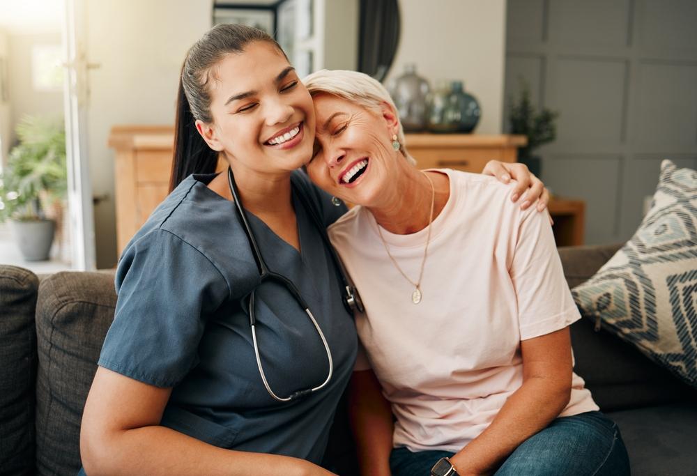 Caregiver sitting on the couch hugging senior